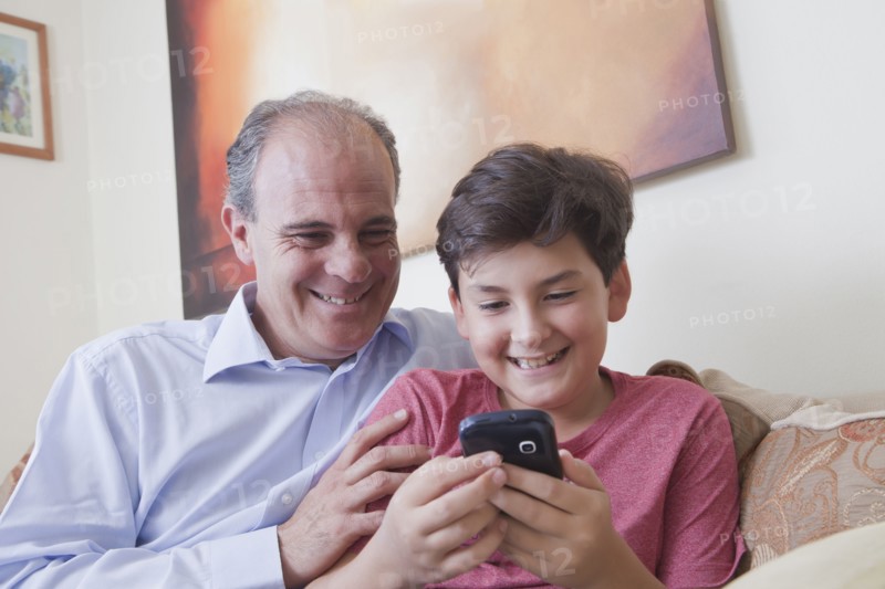 Hispanic father and son texting on cell phone