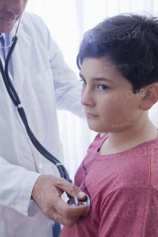 Hispanic doctor listening to chest of boy with stethoscope