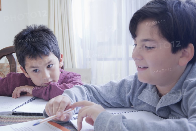 Hispanic brothers doing homework at table