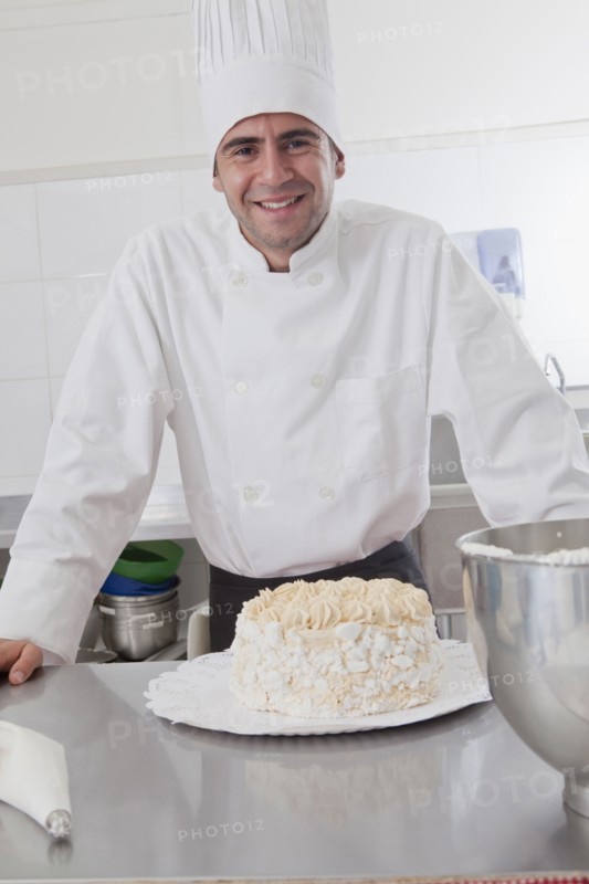 Smiling Hispanic chef posing with cake