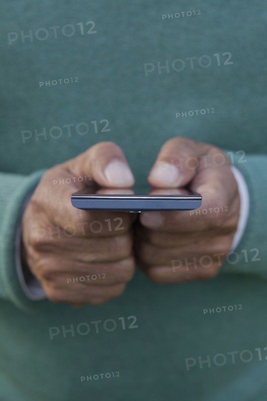 Hands of Hispanic man texting on cell phone