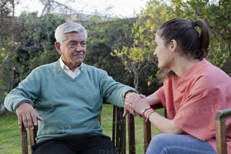 Hispanic nurse comforting man sitting in chair