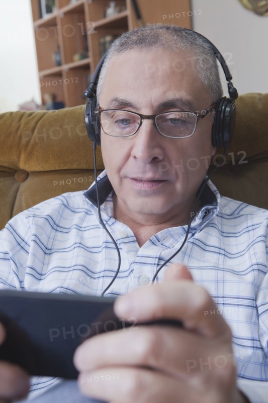 Curious Hispanic man listening to cell phone with headphones
