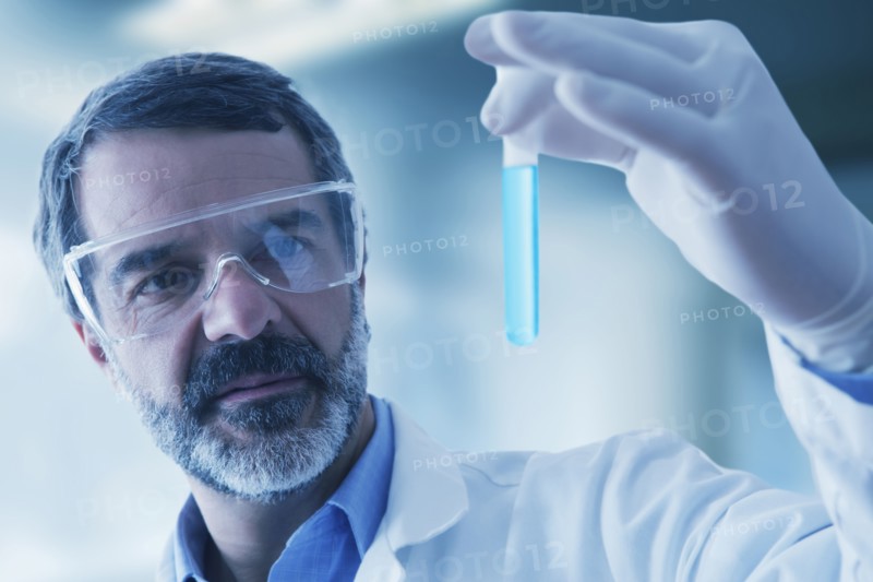 Hispanic researcher holding vial of blue liquid