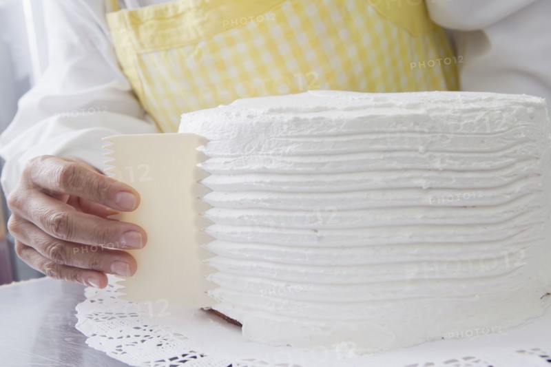 Hispanic woman shaping icing on cake