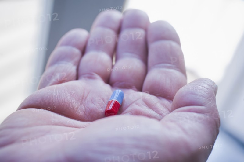 Hand of Hispanic man holding pill