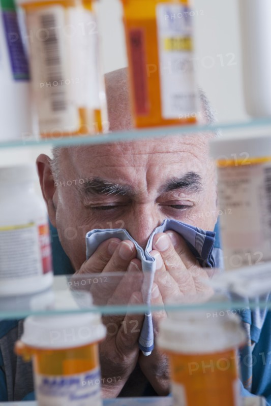Hispanic man wiping nose near medicine cabinet