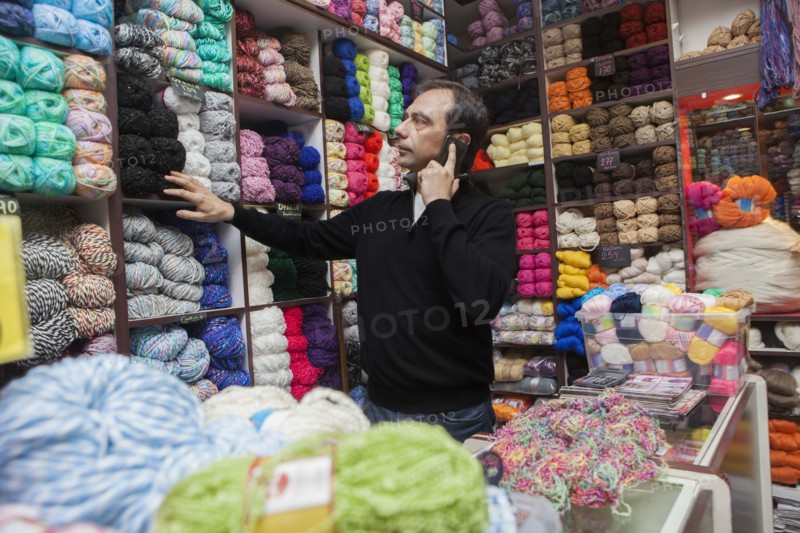 Mixed Race man talking on cell phone at yarn store