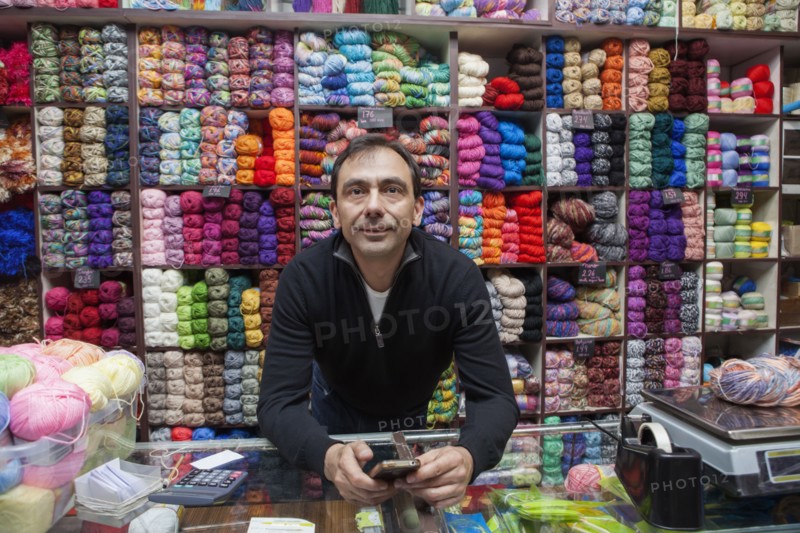 Mixed Race man texting on cell phone at yarn store