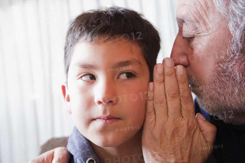 Hispanic grandfather whispering secret to grandson