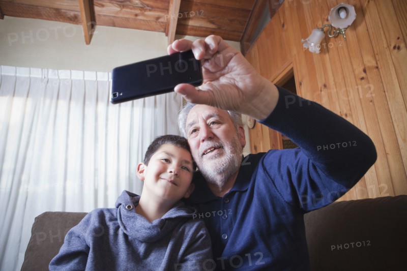 Hispanic grandfather and grandson posing for cell phone selfie