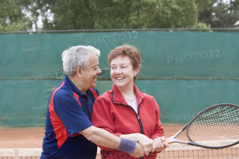 Senior Hispanic man teaching wife to play tennis
