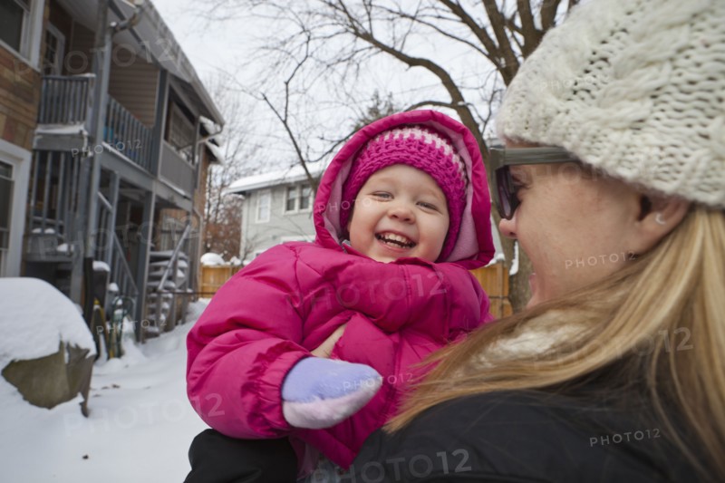 Mother holding grinning girl in coat
