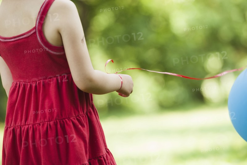 Girl with balloon tied to wrist outdoors