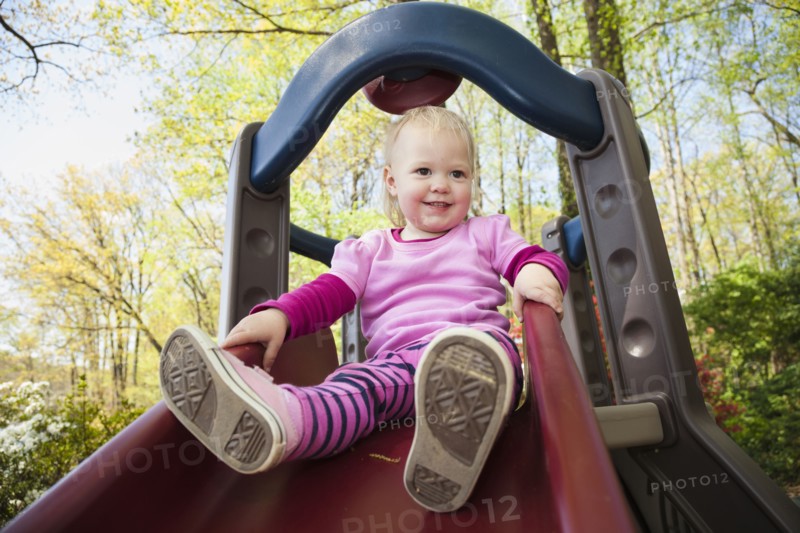Caucasian girl playing on slide outdoors
