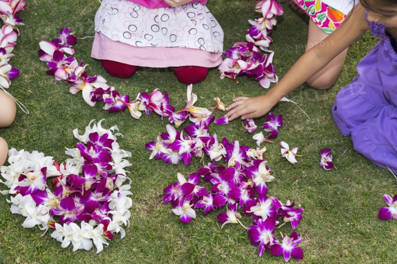 Children playing with flower leis in grass