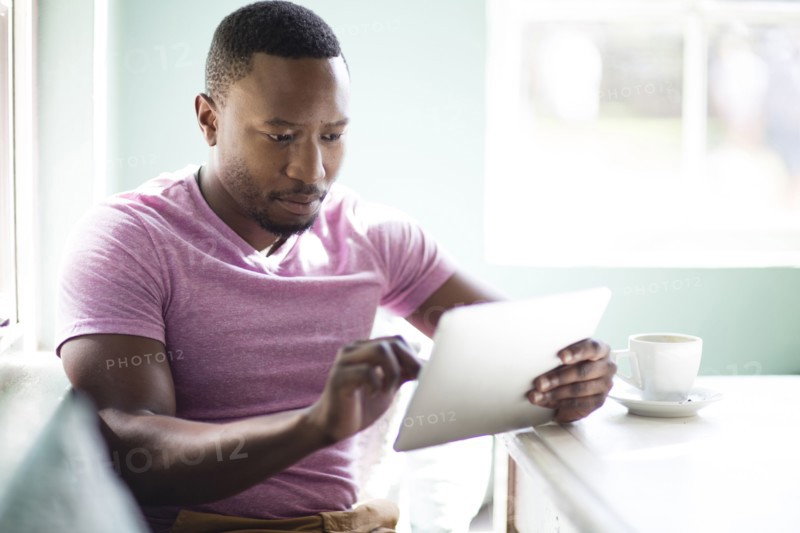Black man using digital tablet at breakfast