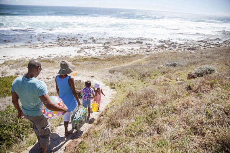 Mixed race family walking on path to beach