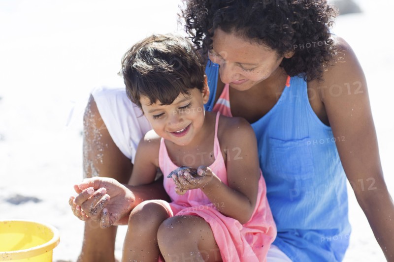 Mixed race mother and daughter playing on beach