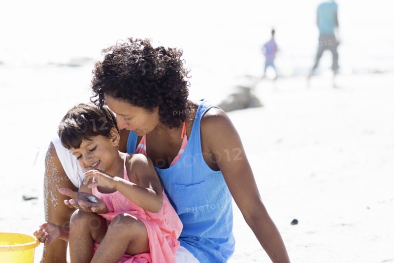 Mixed race mother and daughter playing on beach