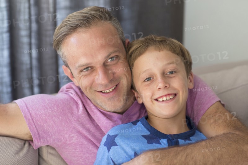 Caucasian father and son hugging on sofa
