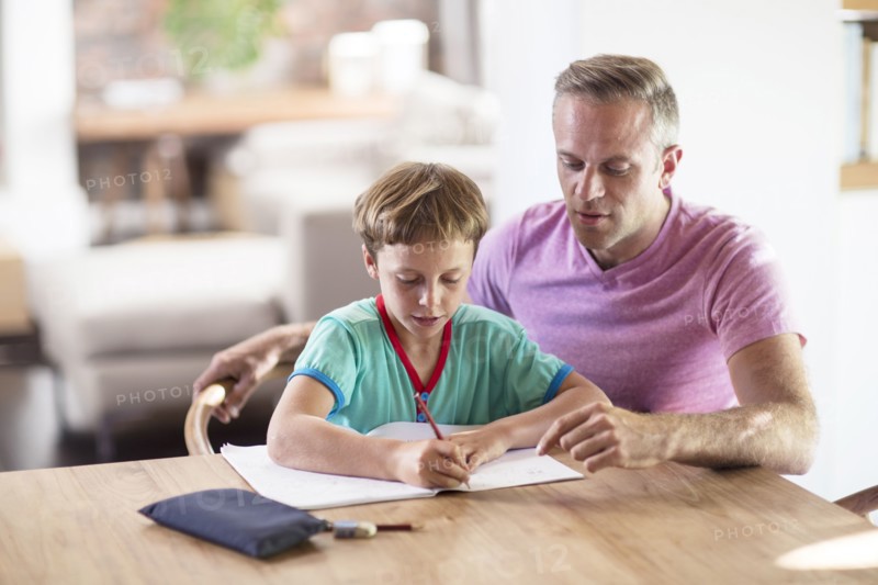 Caucasian father and son drawing at table