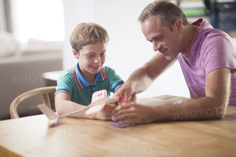 Caucasian father and son examining model airplane at table