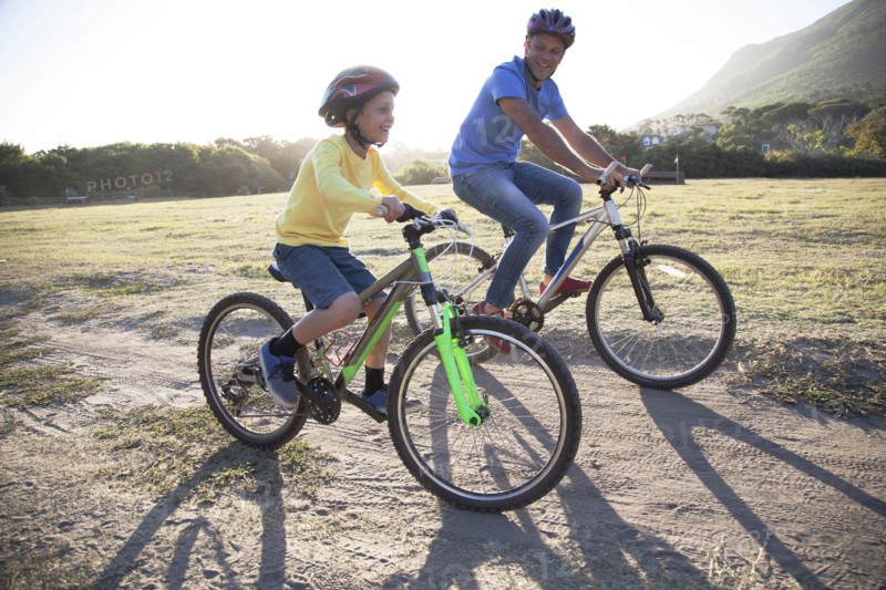 Caucasian father and son riding bicycles on dirt path