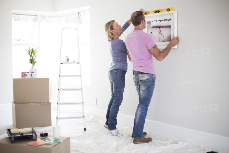 Caucasian couple using level in new home