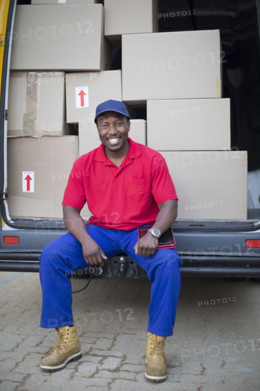 Black delivery man sitting with packages in van