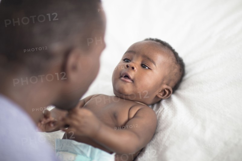 Close up of Black father playing with baby on bed