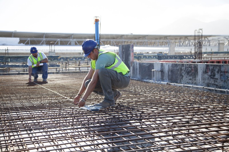 Construction workers arranging rebar at construction site