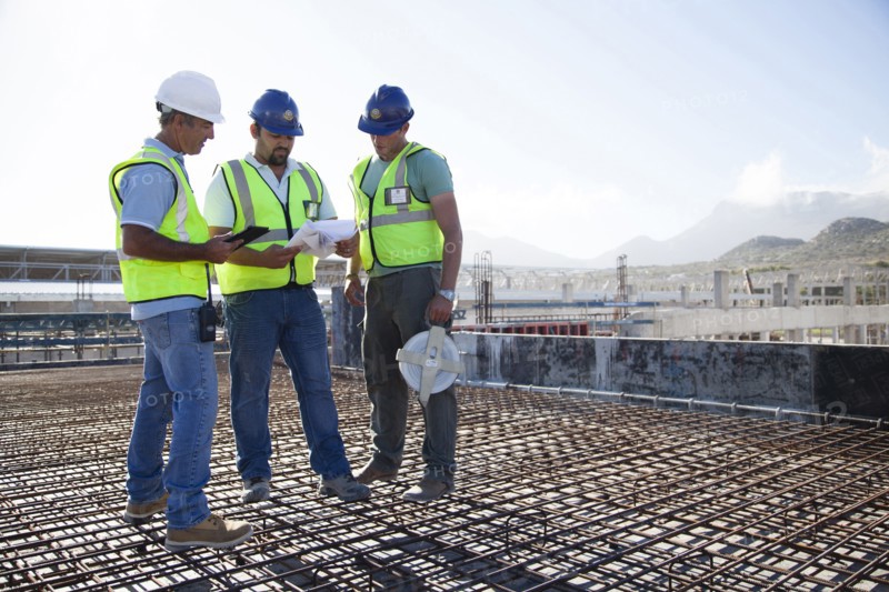 Construction workers talking on rebar at construction site