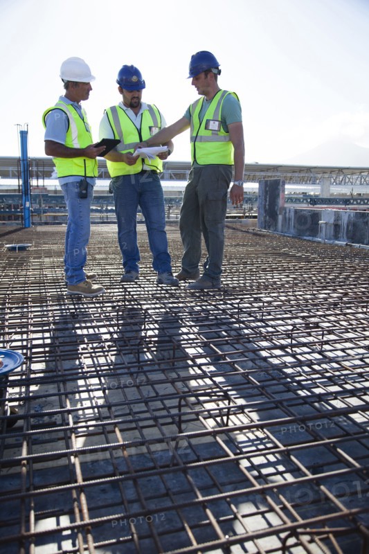 Construction workers talking on rebar at construction site