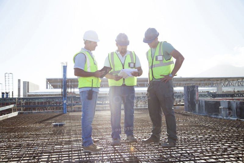 Construction workers talking on rebar at construction site