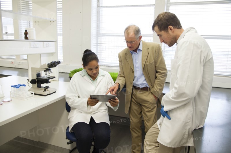 Businessman and scientists using digital tablet in laboratory