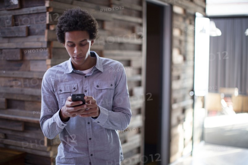 Mixed race businessman using cell phone in hallway