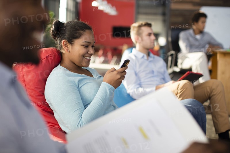 Businesswoman using cell phone in office lounge