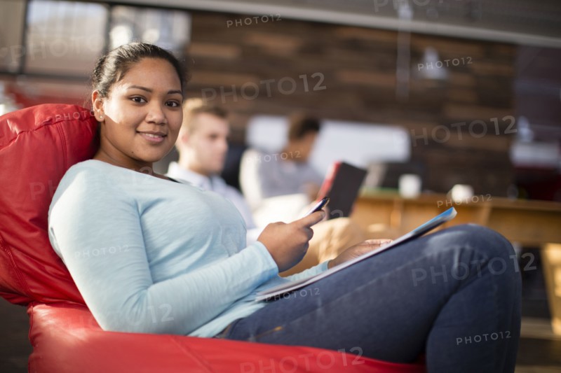 Mixed race businesswoman using cell phone in office lounge