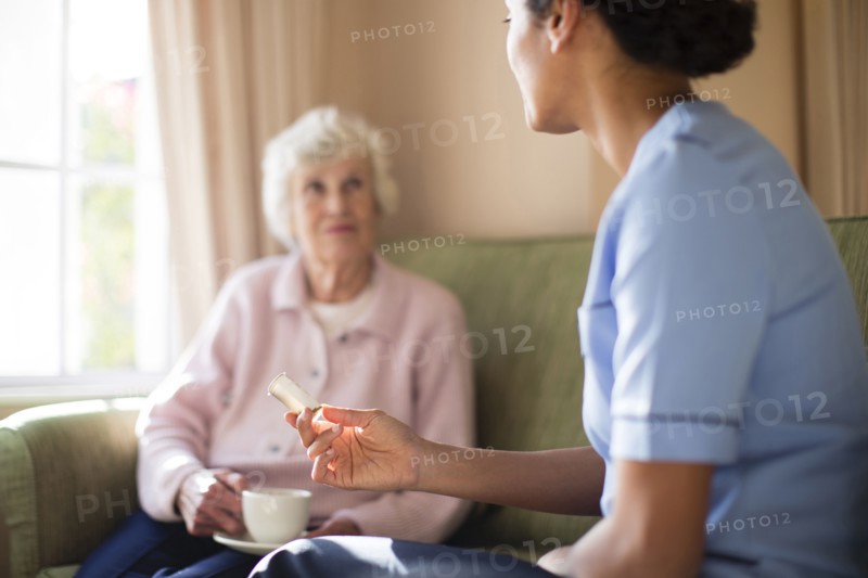 Nurse and patient drinking tea on sofa