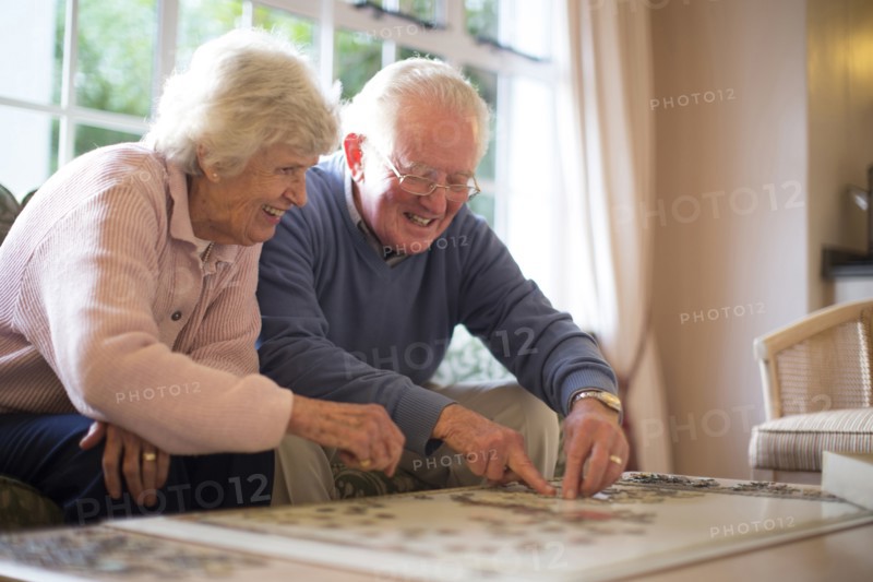 Older couple on sofa solving jigsaw puzzle