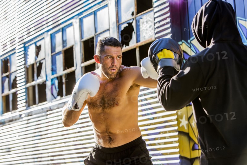 Caucasian boxer sparring with trainer