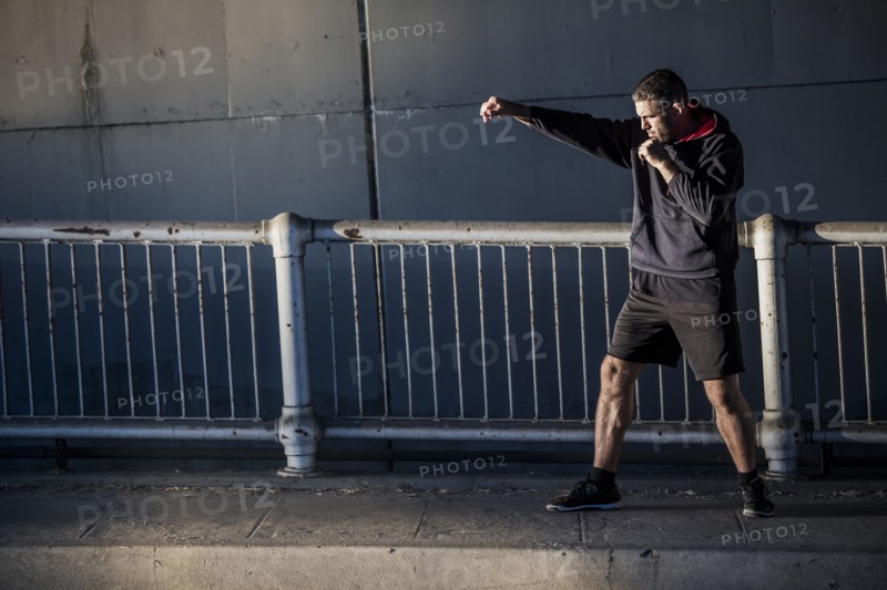 Caucasian man shadow boxing near railing