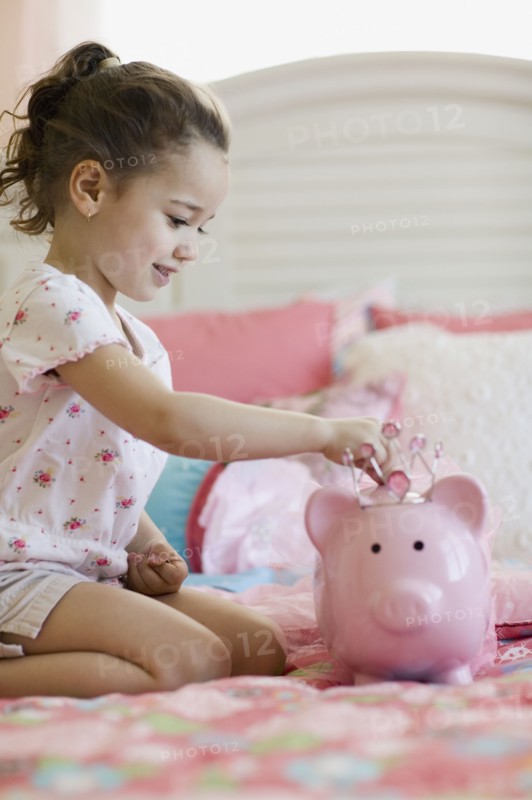 Young girl putting money in piggy bank
