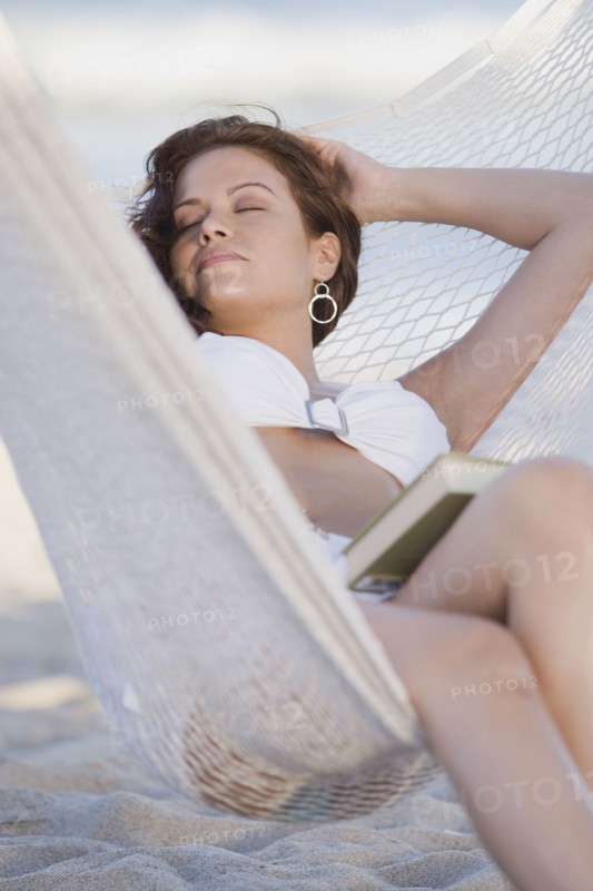 Hispanic woman napping hammock with book