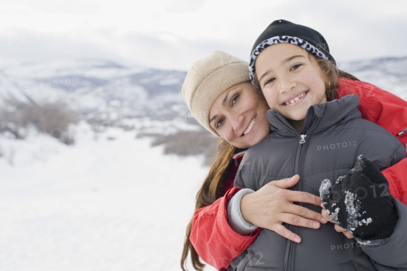 Hispanic mother hugging son in snow field
