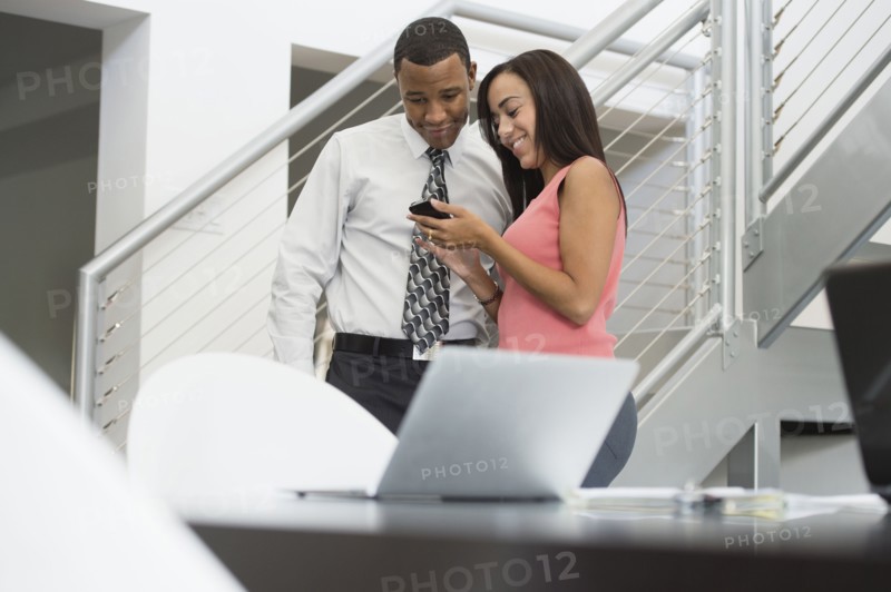 Mixed race business people looking at cell phone