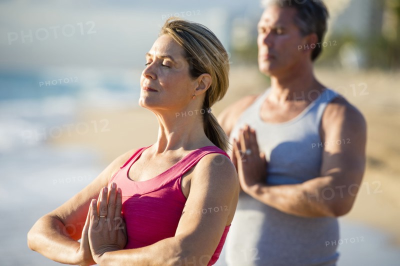 Caucasian couple meditating on beach
