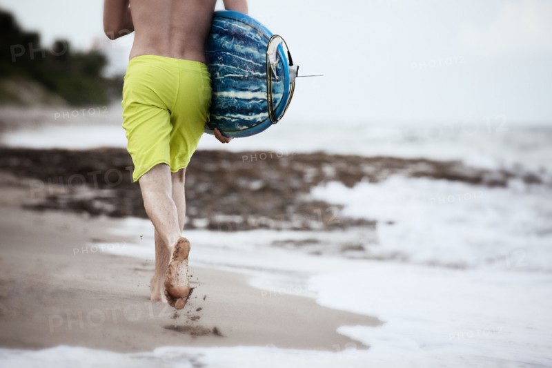 Hispanic man carrying surfboard on beach