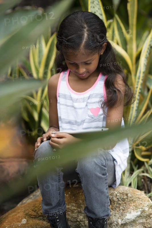 Mixed race girl using digital tablet outdoors